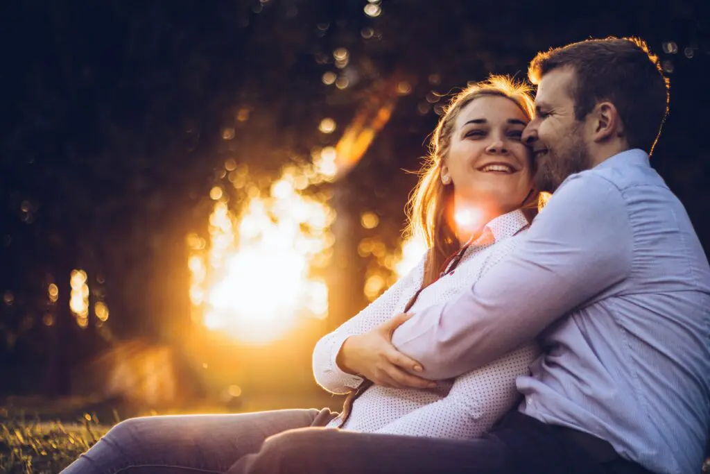 A man and woman hug outdoors in the Summertime.