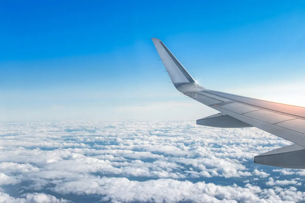 The wing of an airplane over a cloudy sky.