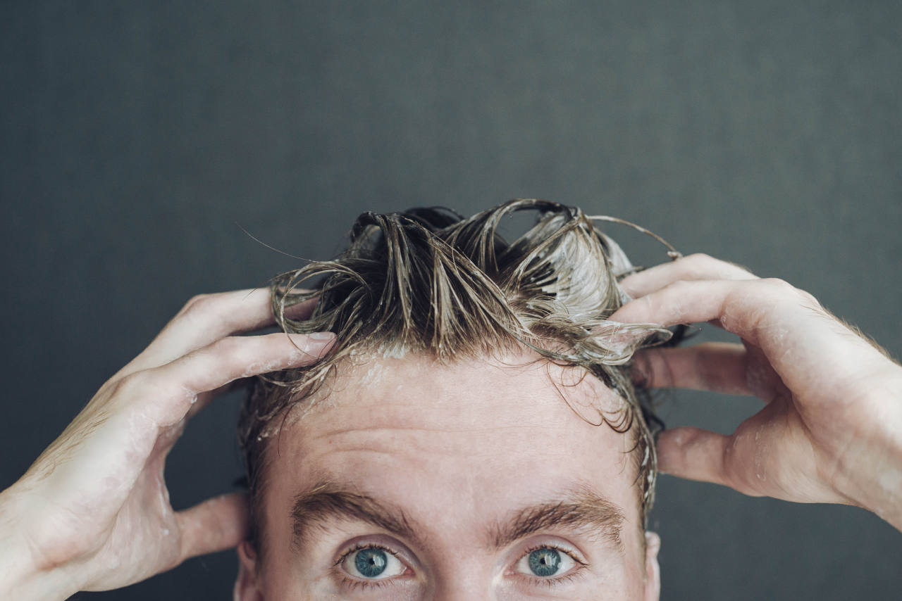 A man applying minoxidil foam to his head