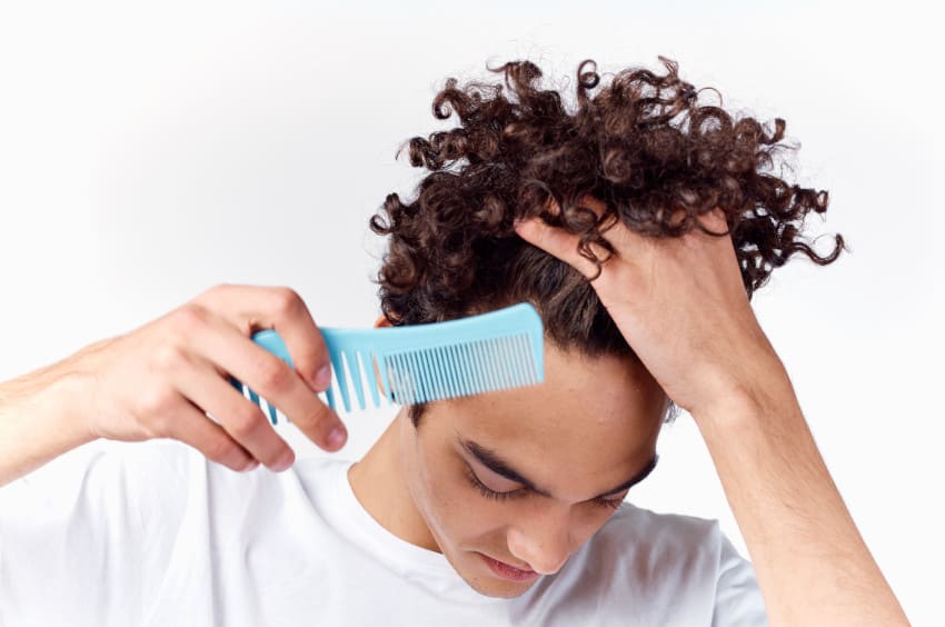 Man with curly hair looks at his receding hair line