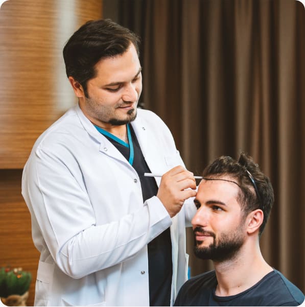 Dr. Balwi examines the scalp and designs a patient's new hairline before his hair transplant at Elithair