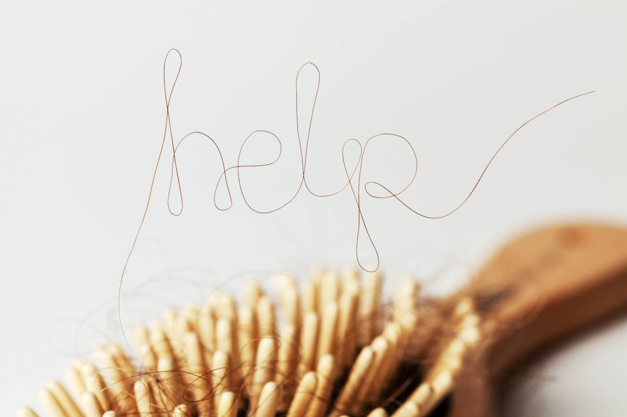 A strand of hair on a hairbrush spelling help