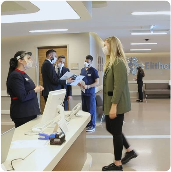 A woman is greeted at the reception desk during corona