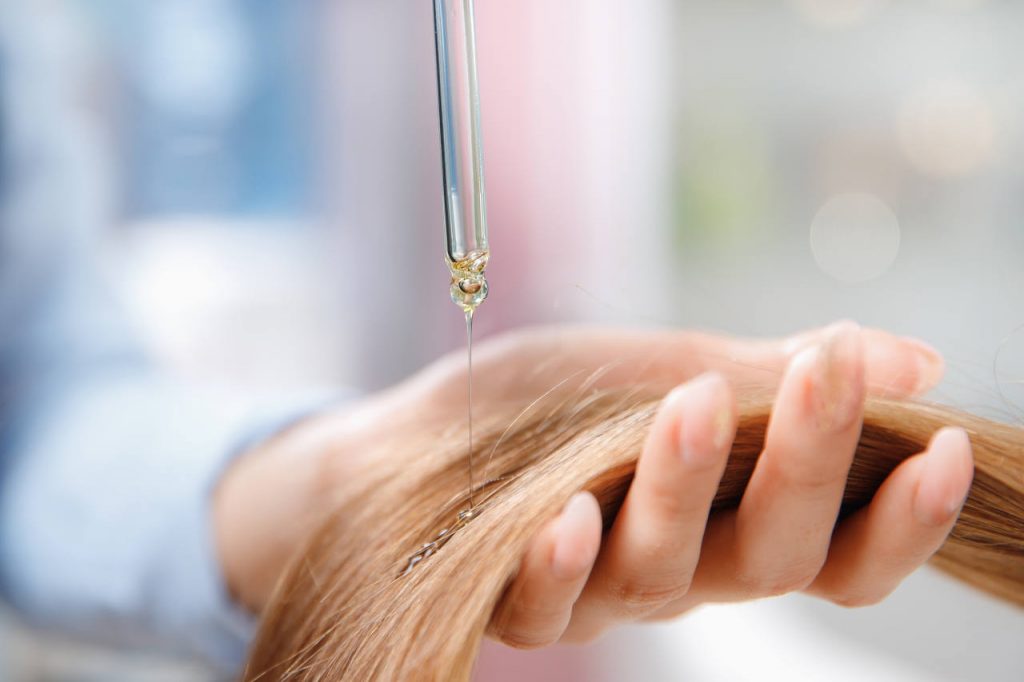 a woman applying oil as a hair fall treatment