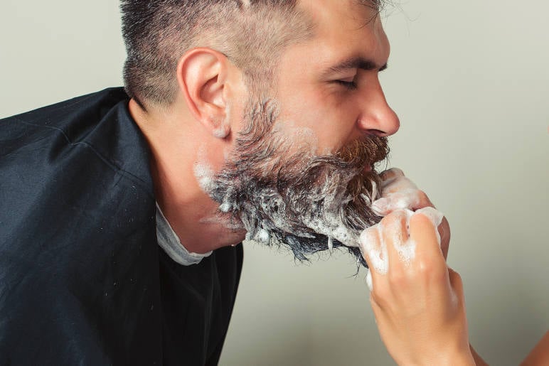 A man having his beard washed by his girlfriend