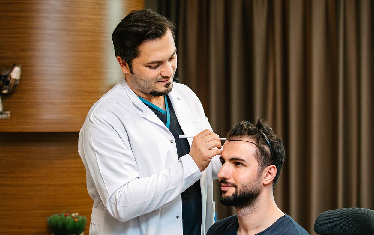 Dr. Balwi designing the frontal hairline before a hair transplant treatment.