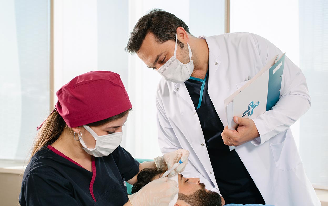 Dr. Balwi oversees his team during a DHI hair transplant operation.