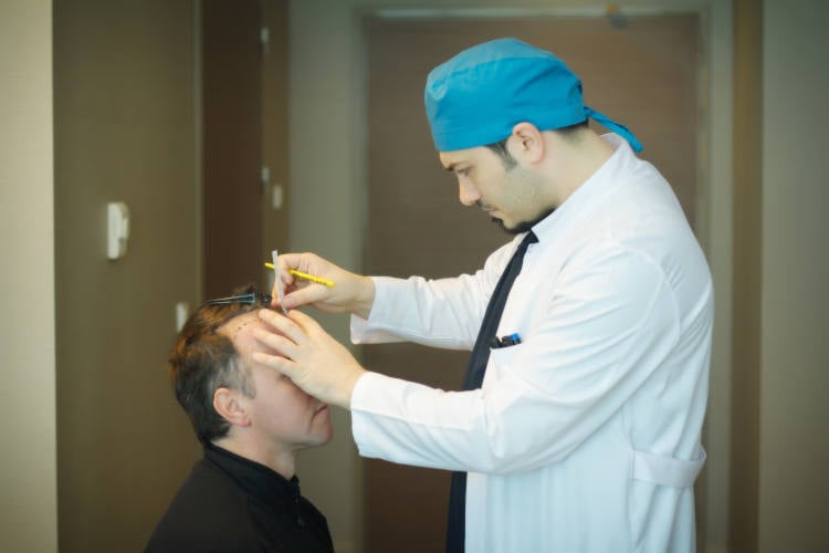 Picture of Dr. Balwi inspecting a patient with a receding hairline
