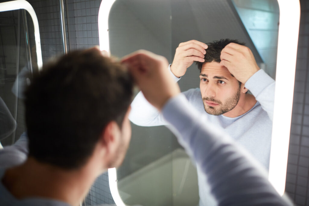 Man parting hairline checking for hair loss