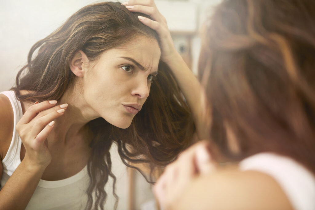 Woman looking in mirror for hair shedding