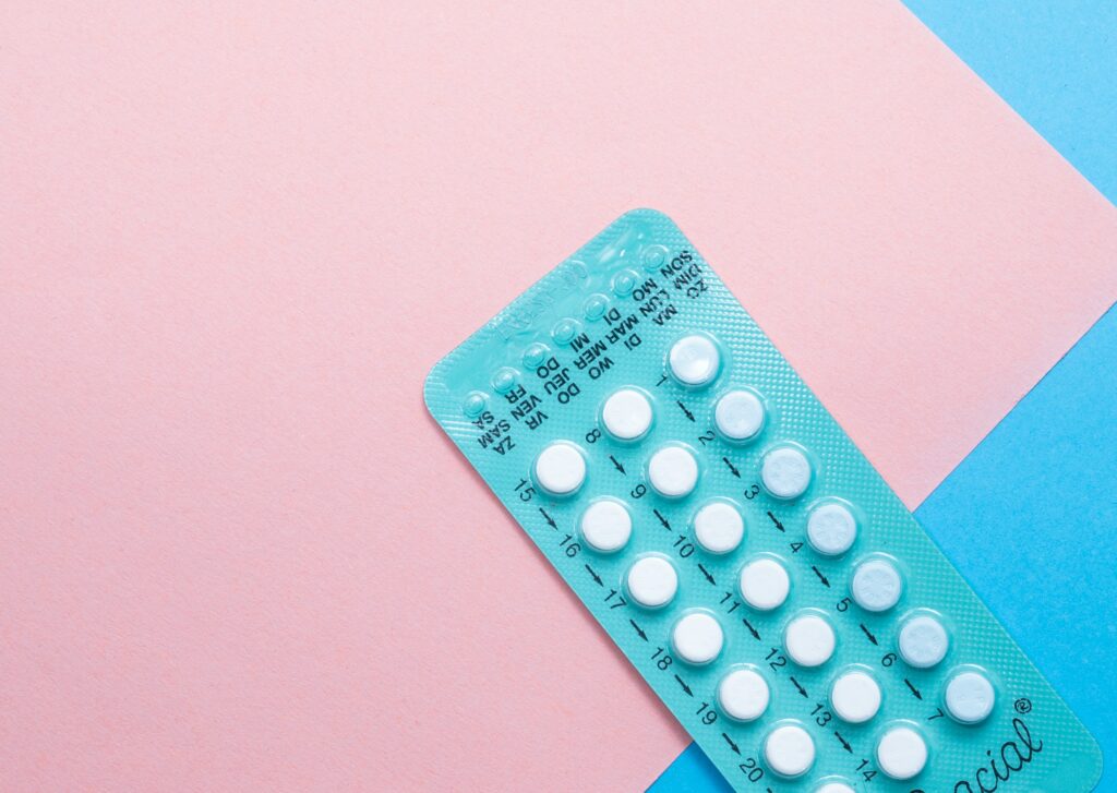 Birth control pills in film on a pink and blue background