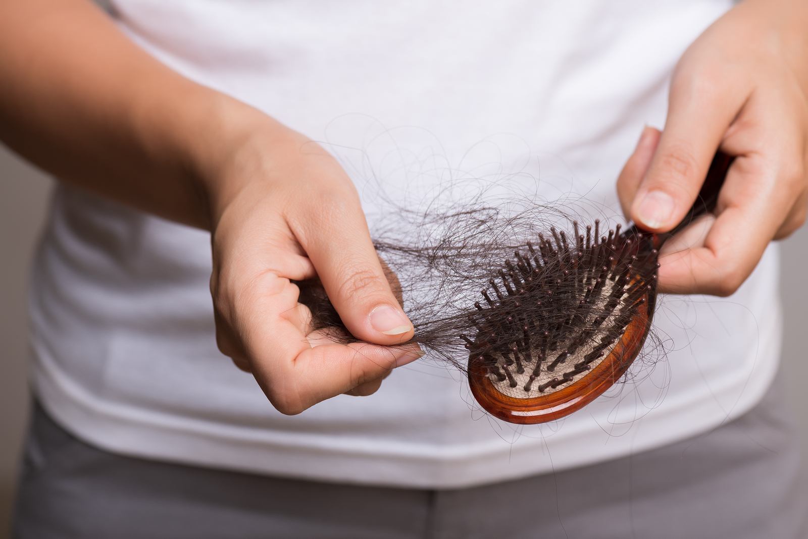 Hair being pulled from a hair brush by a woman