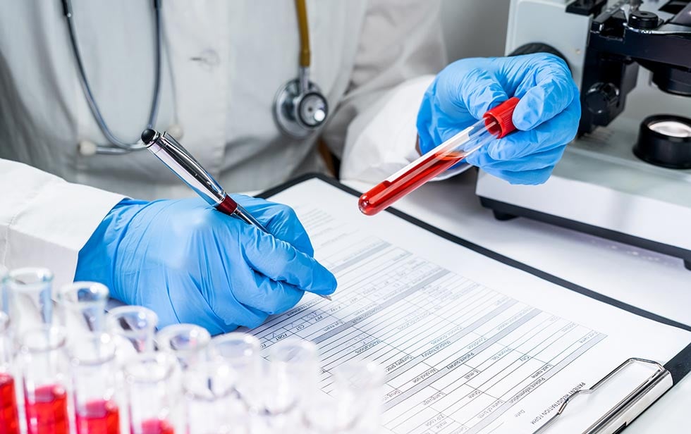 medical staff holding an reviewing a blood vial