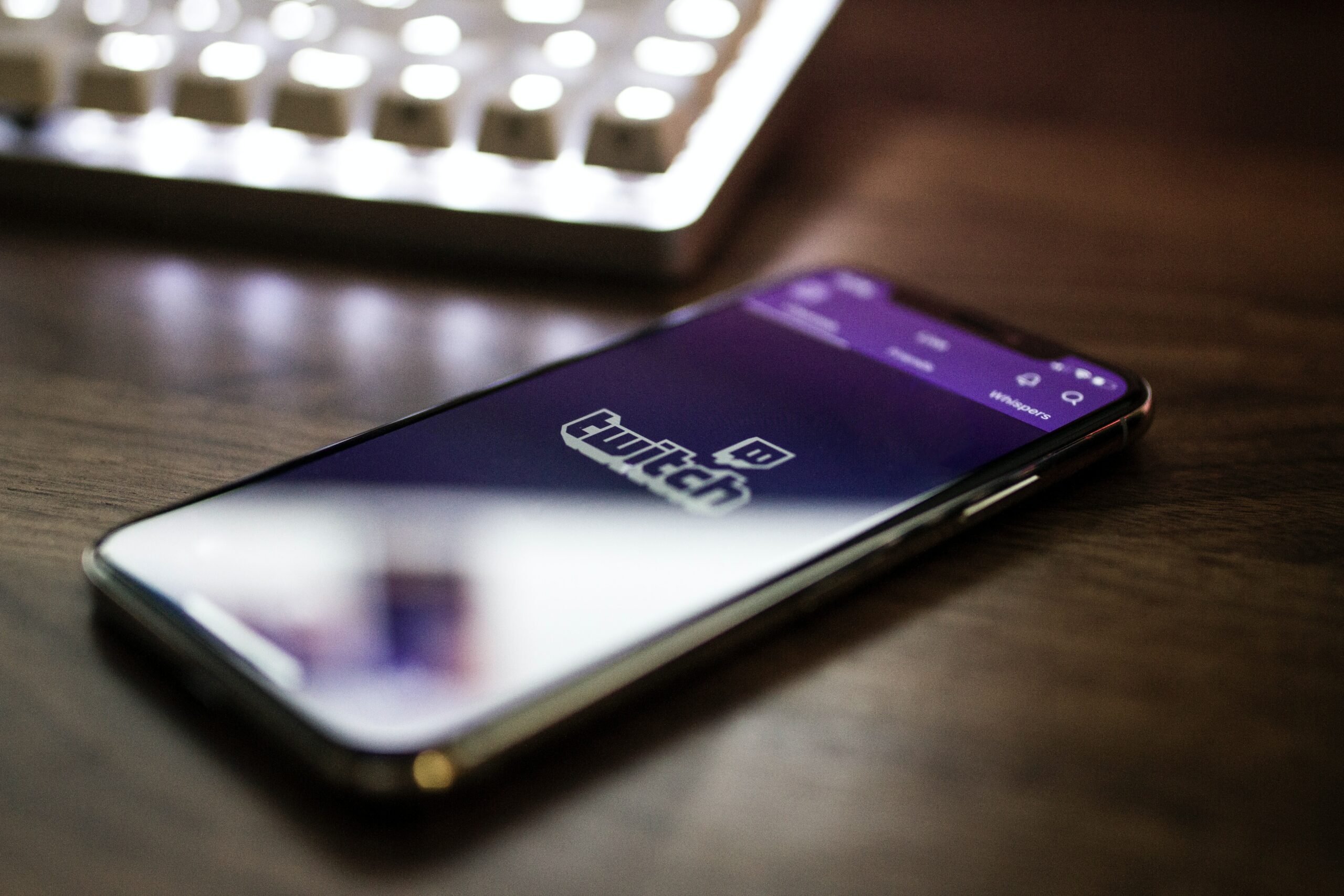 Phone on table showing twitch notification next to keyboard