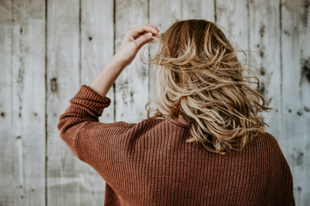 Back of woman with blonde hair running hand through her hair