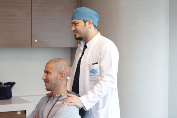 Picture of Dr Balwi examining a patient who has an androgenetic alopecia
