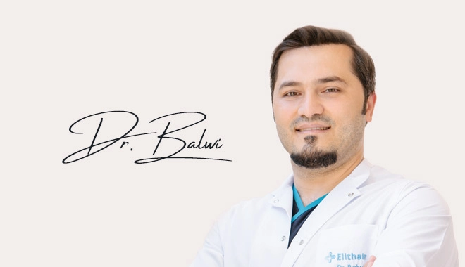 Dr. Balwi in front of a grey background with his signature next to him
