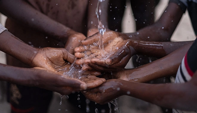 Water pours into the hands of african children