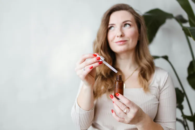 Picutre of a woman holding a hair serum vial