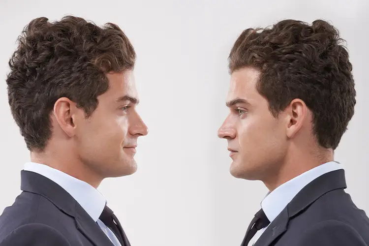 Two identical-looking men look at each other – symbolic image for cloning, genetics and future technologies
