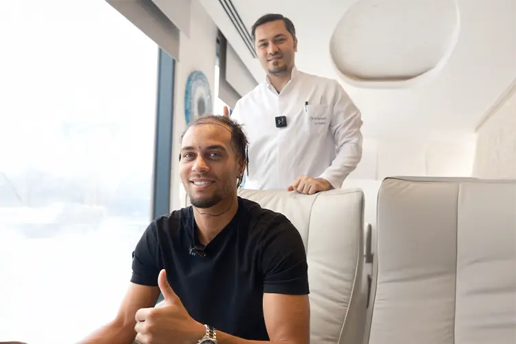 Ouzy See gives a thumbs up. Behind him, Dr. Balwi assesses him before surgery.