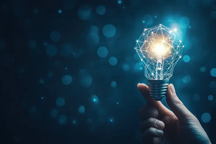 An illustration of a hand holding an illuminated lightbulb against a dark background.