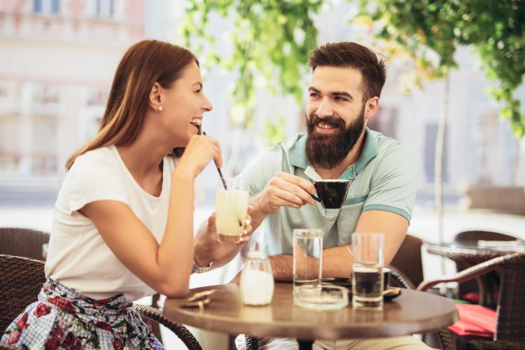 A smiling and laughing couple enjoying some drinks on their first date.