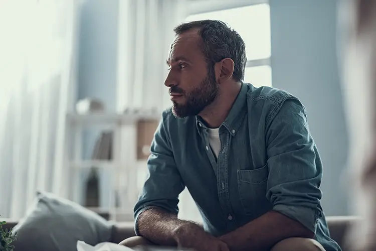 A man with a receding hairline sits alone, pensive.