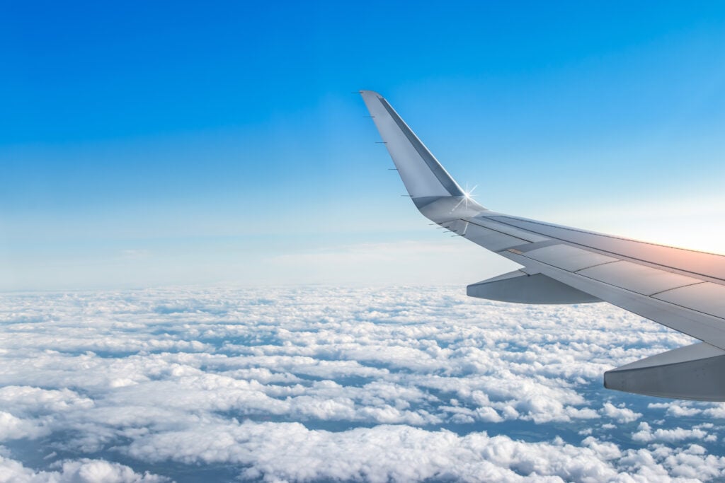 The wing of an airplane over a cloudy sky.