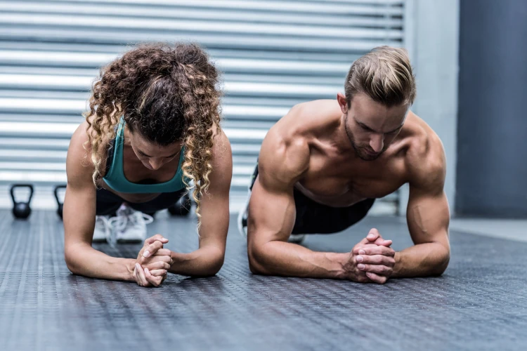 A fit man and woman working out doing planks.