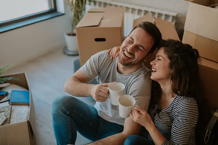 A happy couple laughs and drinks coffee together.