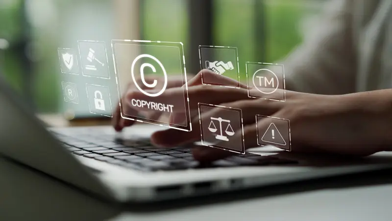 A person types on a laptop overlaid with legal symbols