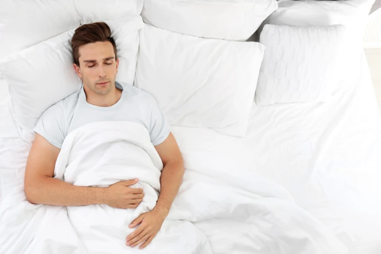 A man sleeping on his back with his head slightly elevated.