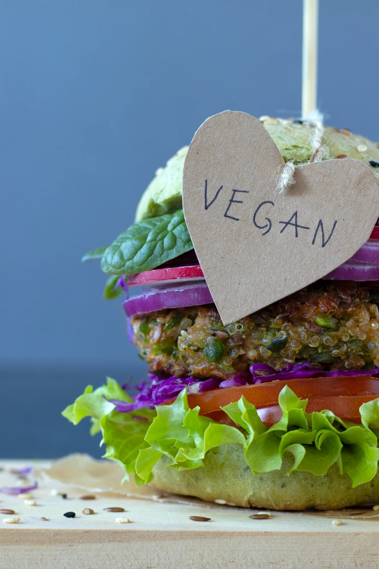 A quinoa burger with a little tag on the top of it that reads “vegan.”