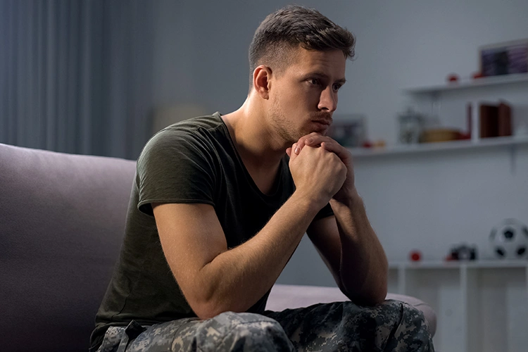 A man sits, looking pensive.