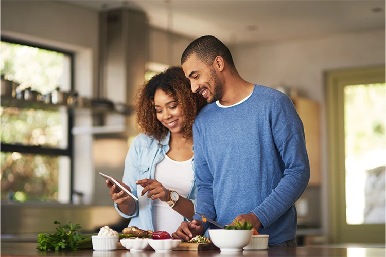 A man and woman smile together in their kitchen.