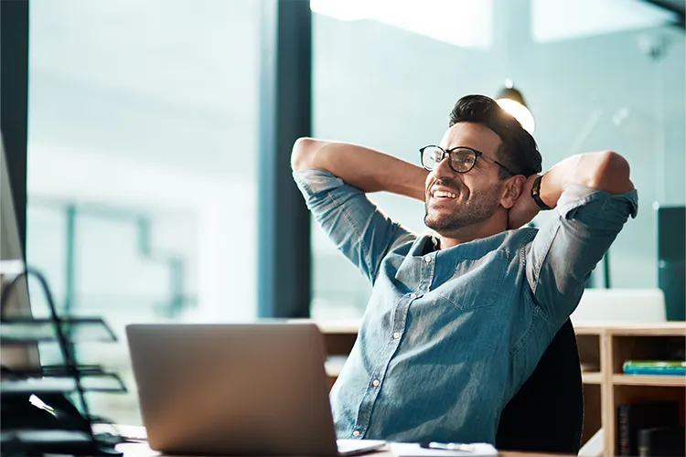 A happy man relaxes in front of his laptop.