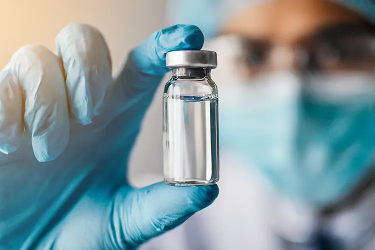 A scientist holds a vial of liquid in a lab.