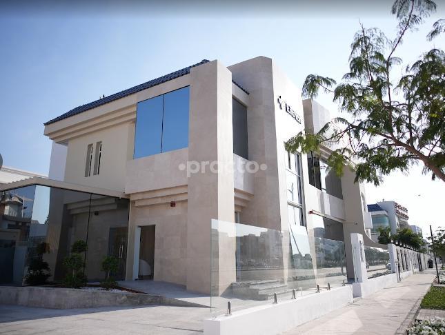 Outside view of Elithair Dubai's hair loss clinic building with large glass windows, light stone exterior, and a clean pavement surrounded by trees.