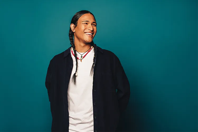 A Native American man with his hair in two braids smiles.